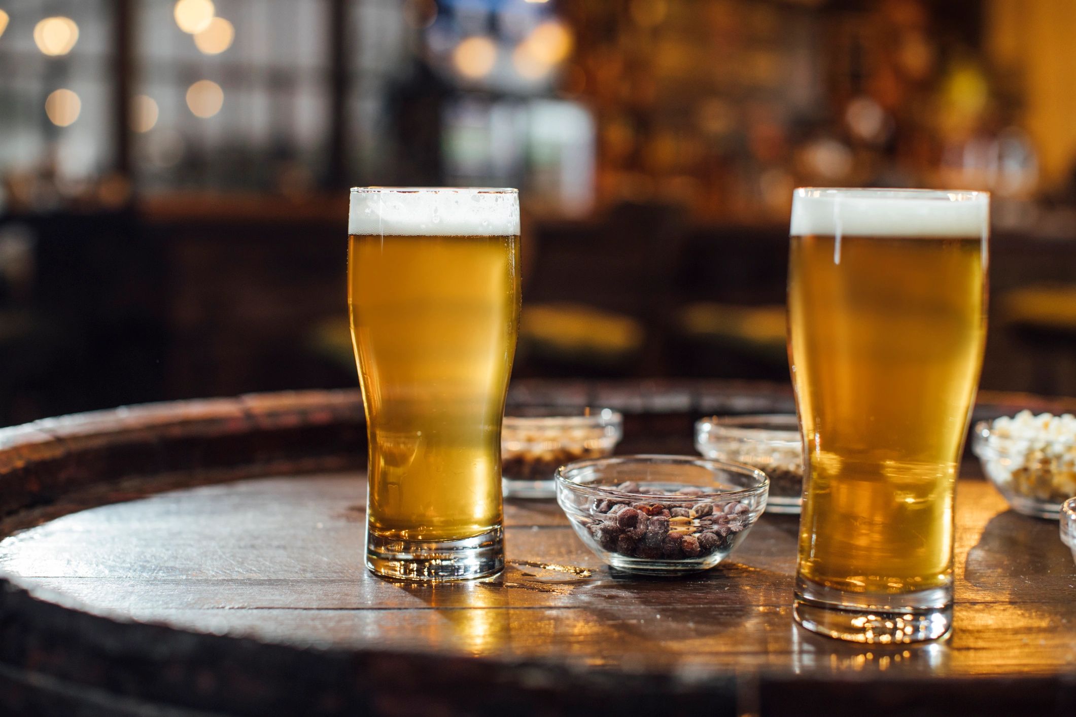 Pint of beer on a wooden table with snacks